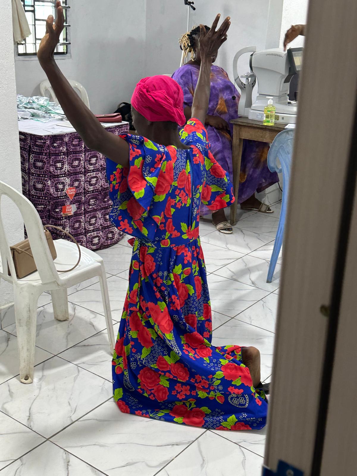 A woman kneeling in prayer with hands raised